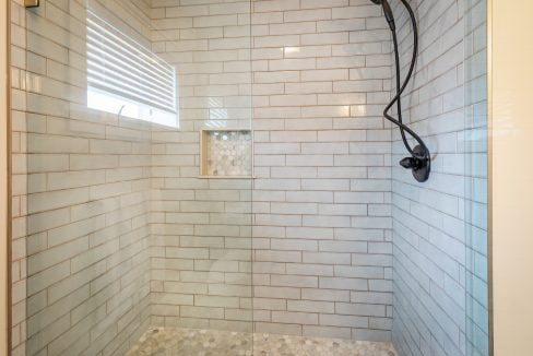 a white tiled shower with a glass door.