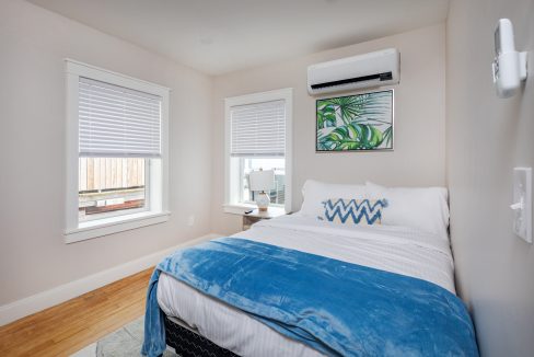 a bedroom with a bed, window, and air conditioner.