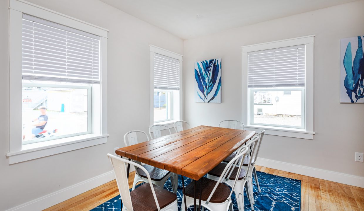 a dining room with a wooden table surrounded by white chairs.