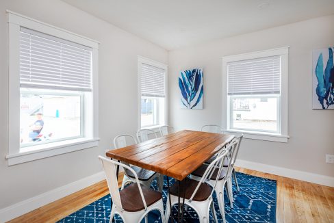 a dining room with a wooden table surrounded by white chairs.