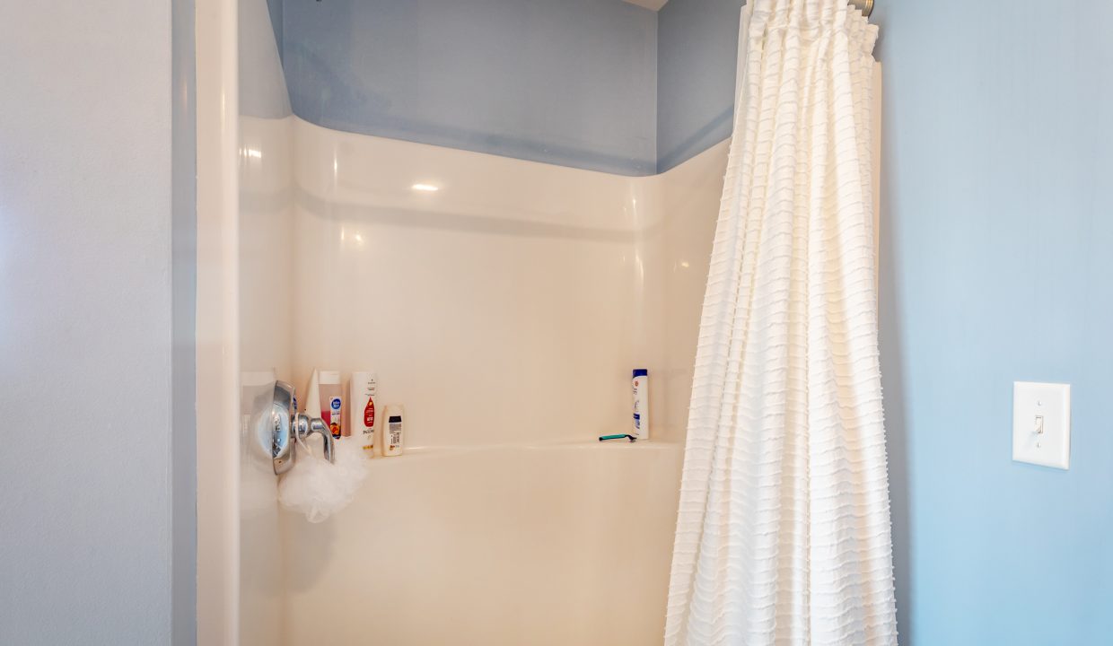 a bathroom with a white shower curtain and blue walls.