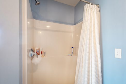 a bathroom with a white shower curtain and blue walls.