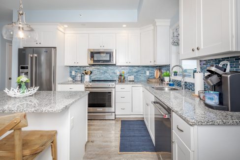 a kitchen with white cabinets and silver appliances.