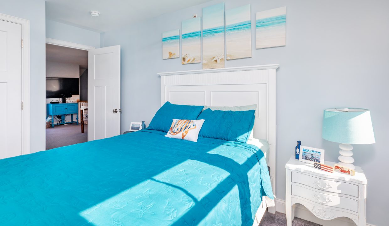 a bedroom with a blue bed and a white dresser.