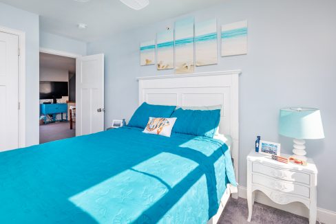 a bedroom with a blue bed and a white dresser.