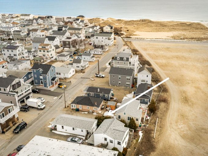Aerial view of a coastal neighborhood with tightly packed houses adjacent to a sandy beach.