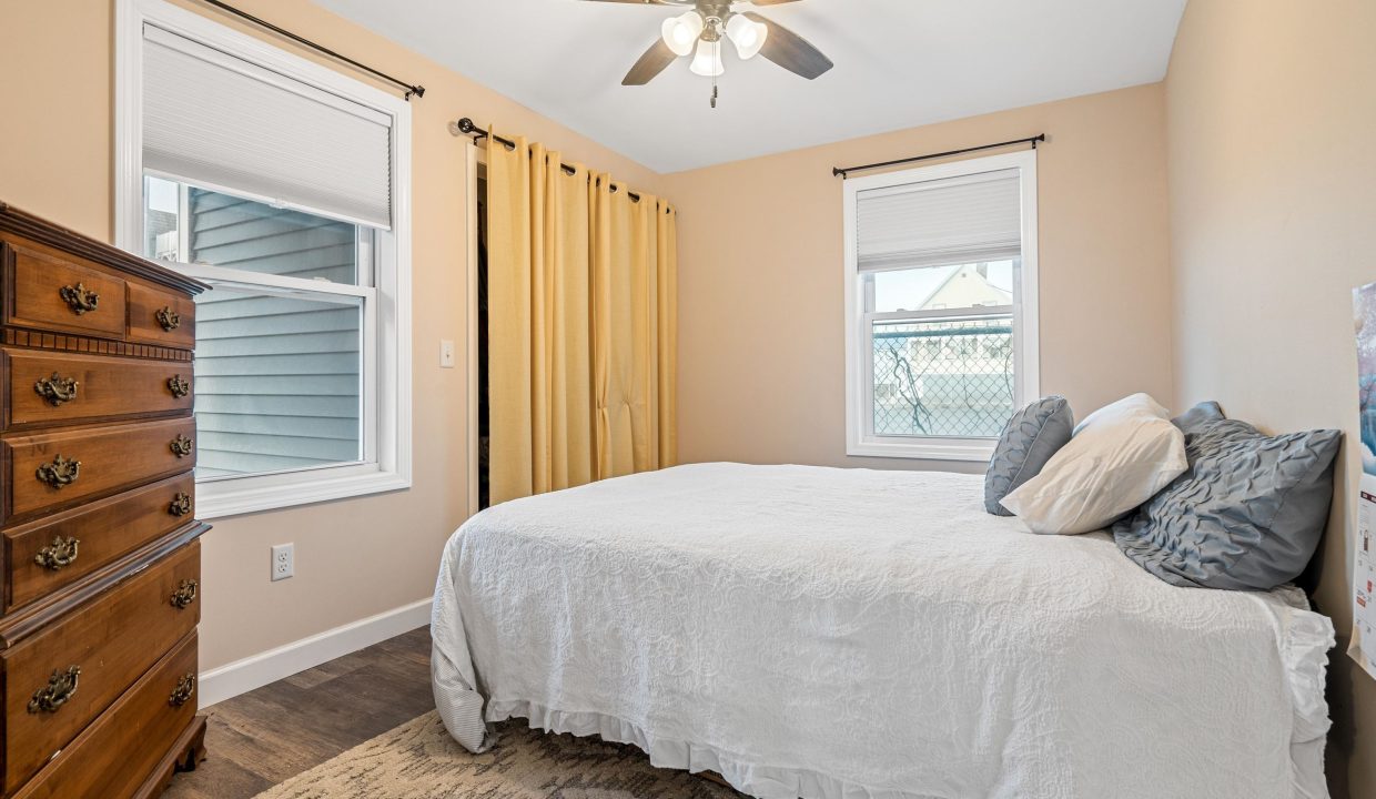 a bedroom with a bed, dresser, and ceiling fan.