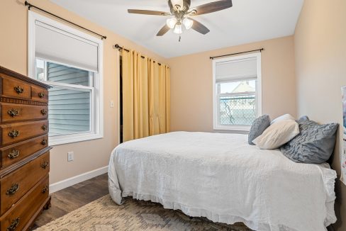 a bedroom with a bed, dresser, and ceiling fan.