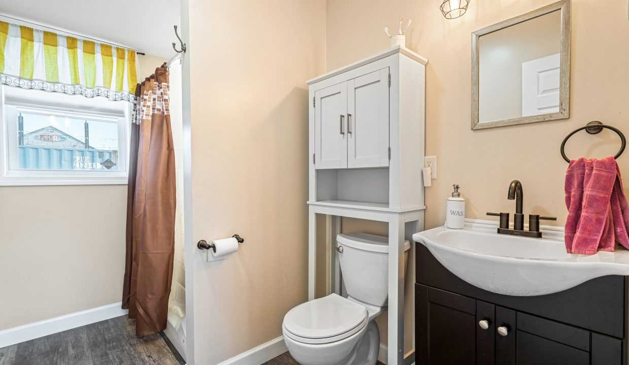 a bathroom with a toilet, sink, and mirror.