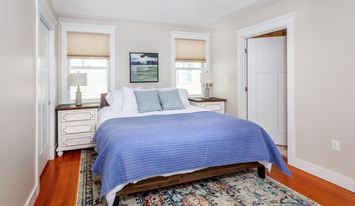 a bedroom with a bed and a rug on the floor.