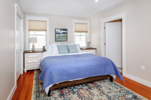 a bedroom with a bed and a rug on the floor.