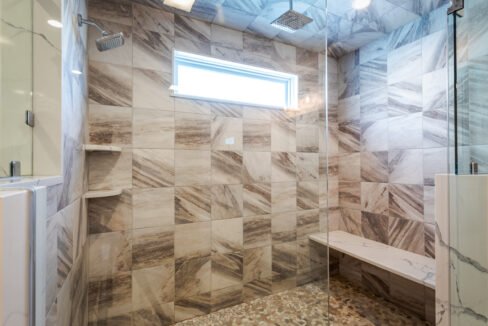 a bathroom with a glass shower door and tiled walls.