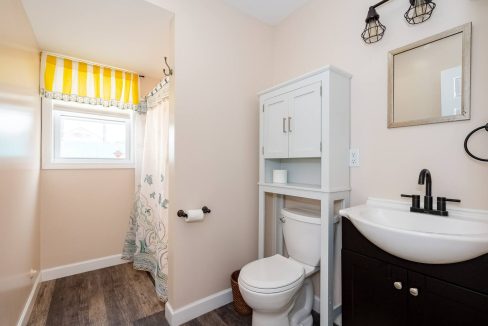 A bright, clean bathroom with white walls, a dark vanity, and a patterned shower curtain.