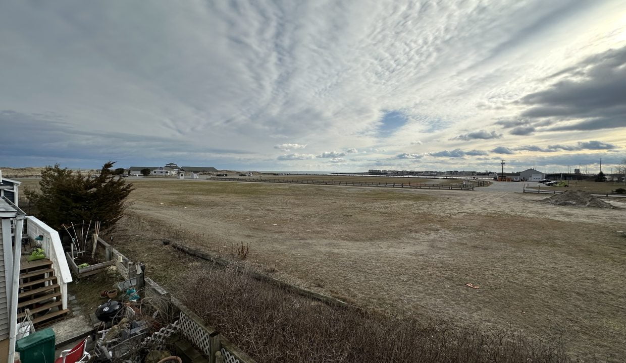 a large open field with a house in the distance.