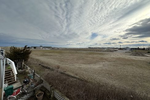 a large open field with a house in the distance.