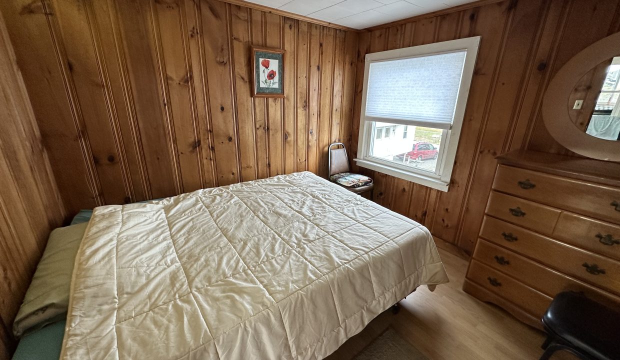 a bedroom with wood paneling and a bed.