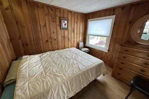 a bedroom with wood paneling and a bed.