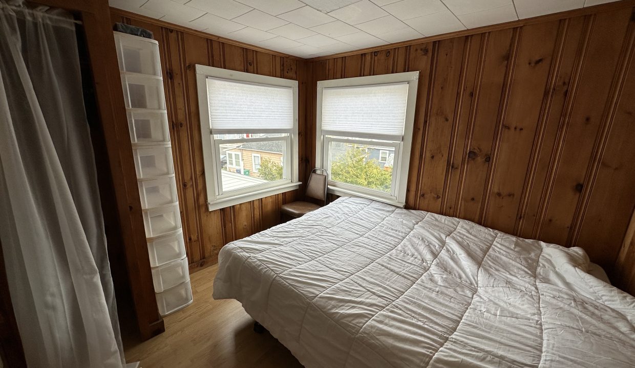 a bedroom with wood paneling and a white bed.