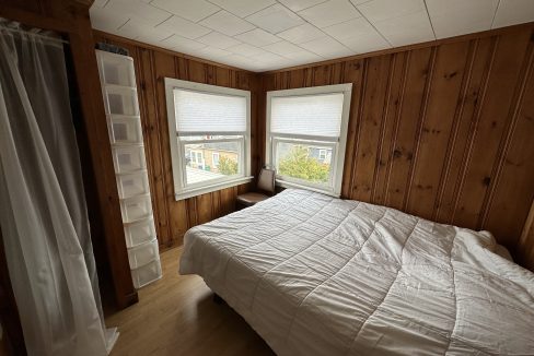 a bedroom with wood paneling and a white bed.