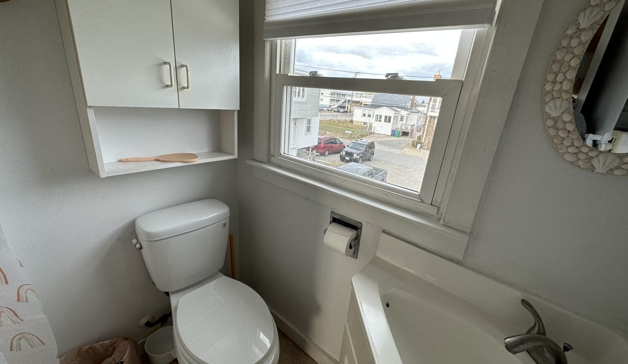 a white toilet sitting next to a window in a bathroom.