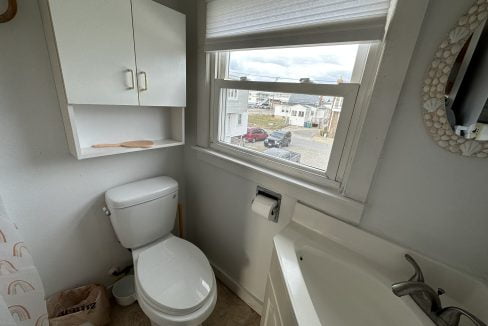 a white toilet sitting next to a window in a bathroom.