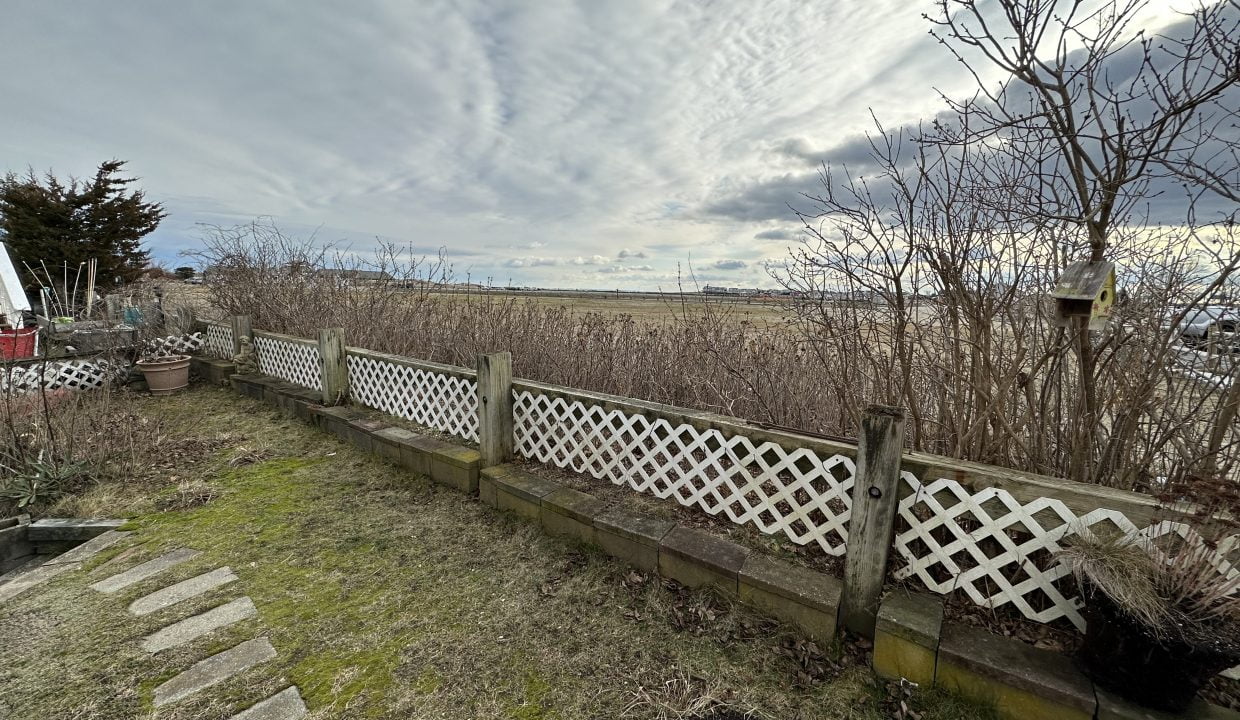 a wooden fence in a grassy area next to a field.