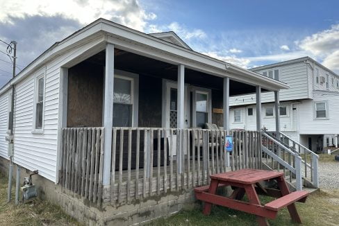 a small white house with a red bench in front of it.