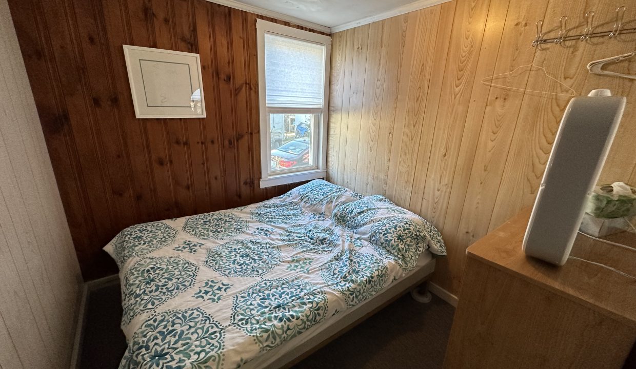 a bedroom with wood paneling and a bed.