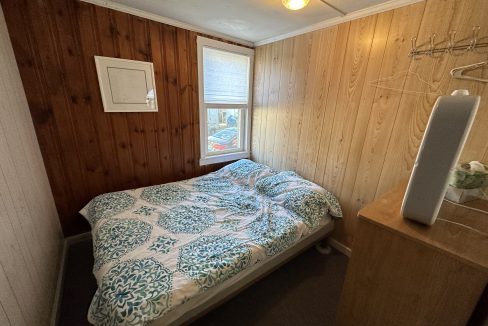 a bedroom with wood paneling and a bed.