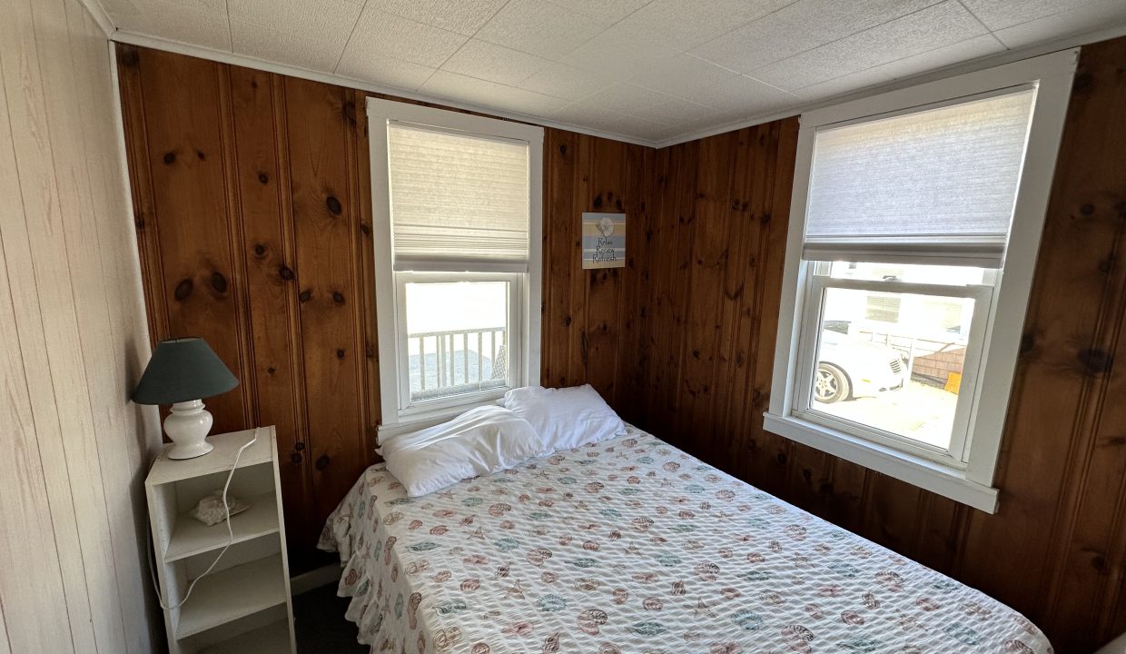 a bed sitting in a bedroom next to two windows.