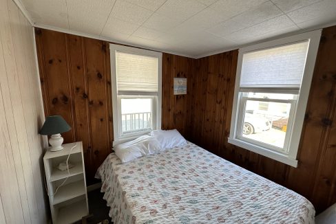 a bed sitting in a bedroom next to two windows.