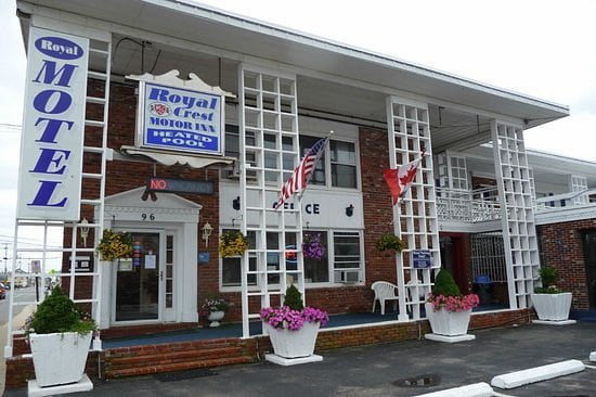 the front of a motel with flags and flowers.
