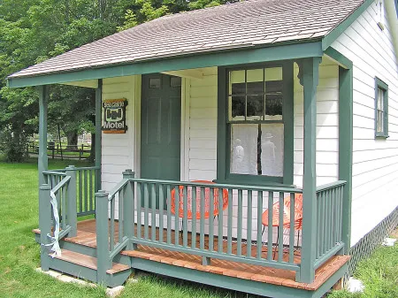 a small white and green house with a porch.