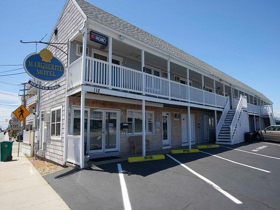 a white building with a blue sign and a car parked in front of it.