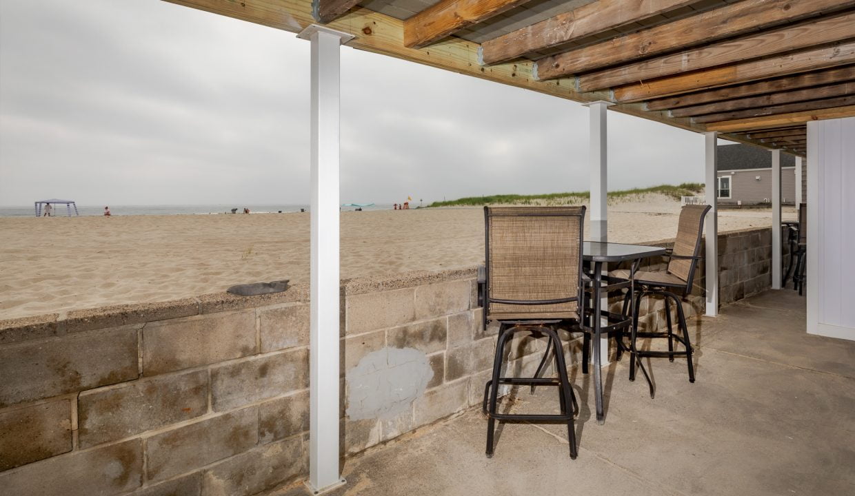 a balcony with a table and chairs overlooking the beach.