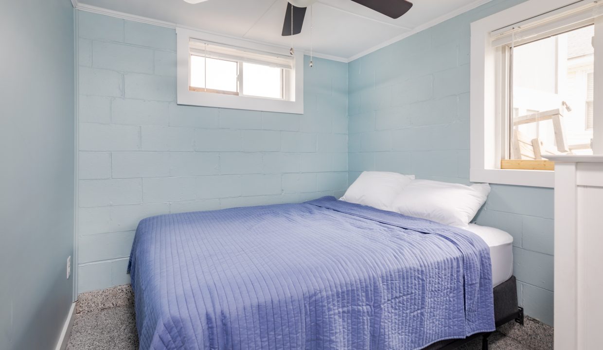 a bedroom with blue walls and a ceiling fan.