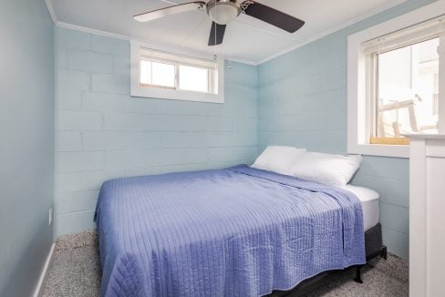 a bedroom with blue walls and a ceiling fan.