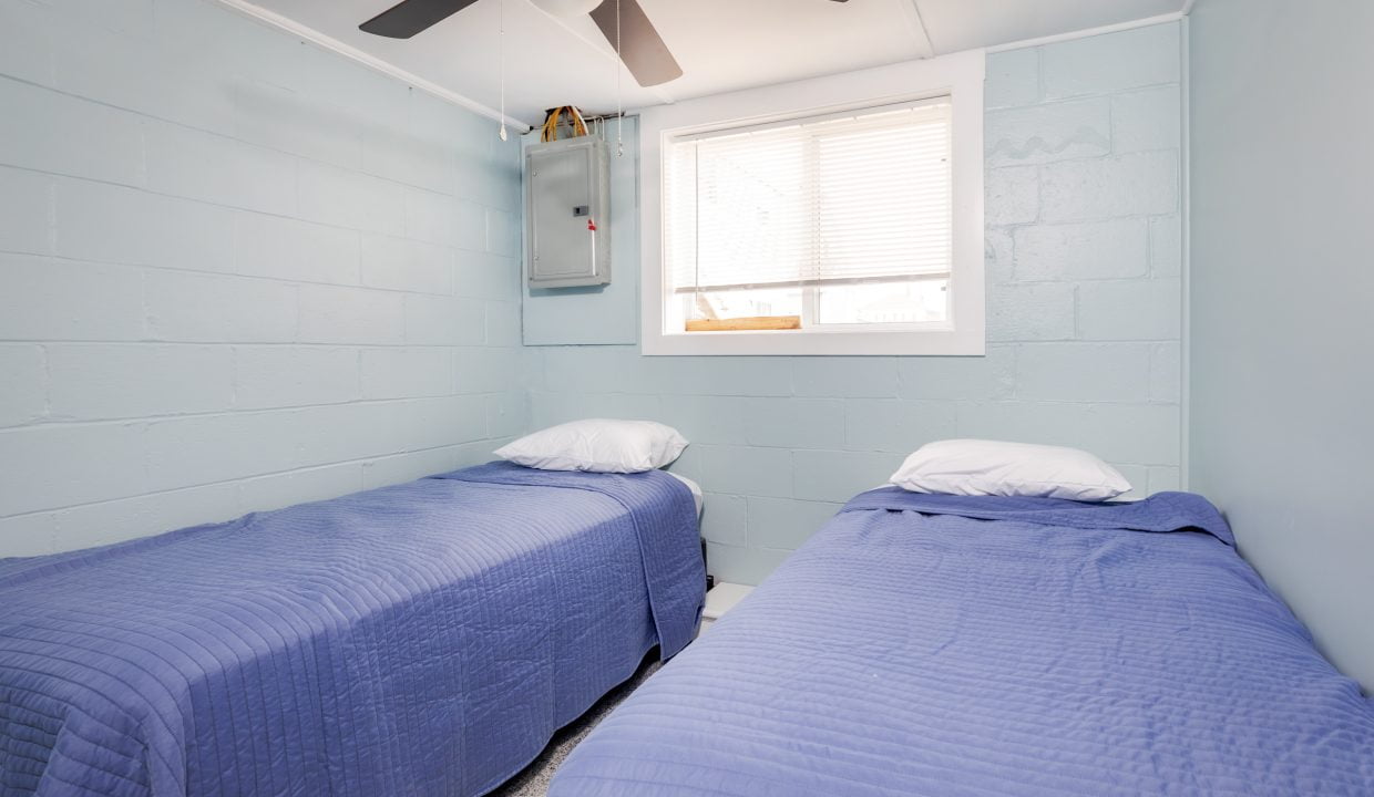 two beds in a room with a ceiling fan.