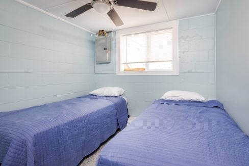 two beds in a room with a ceiling fan.