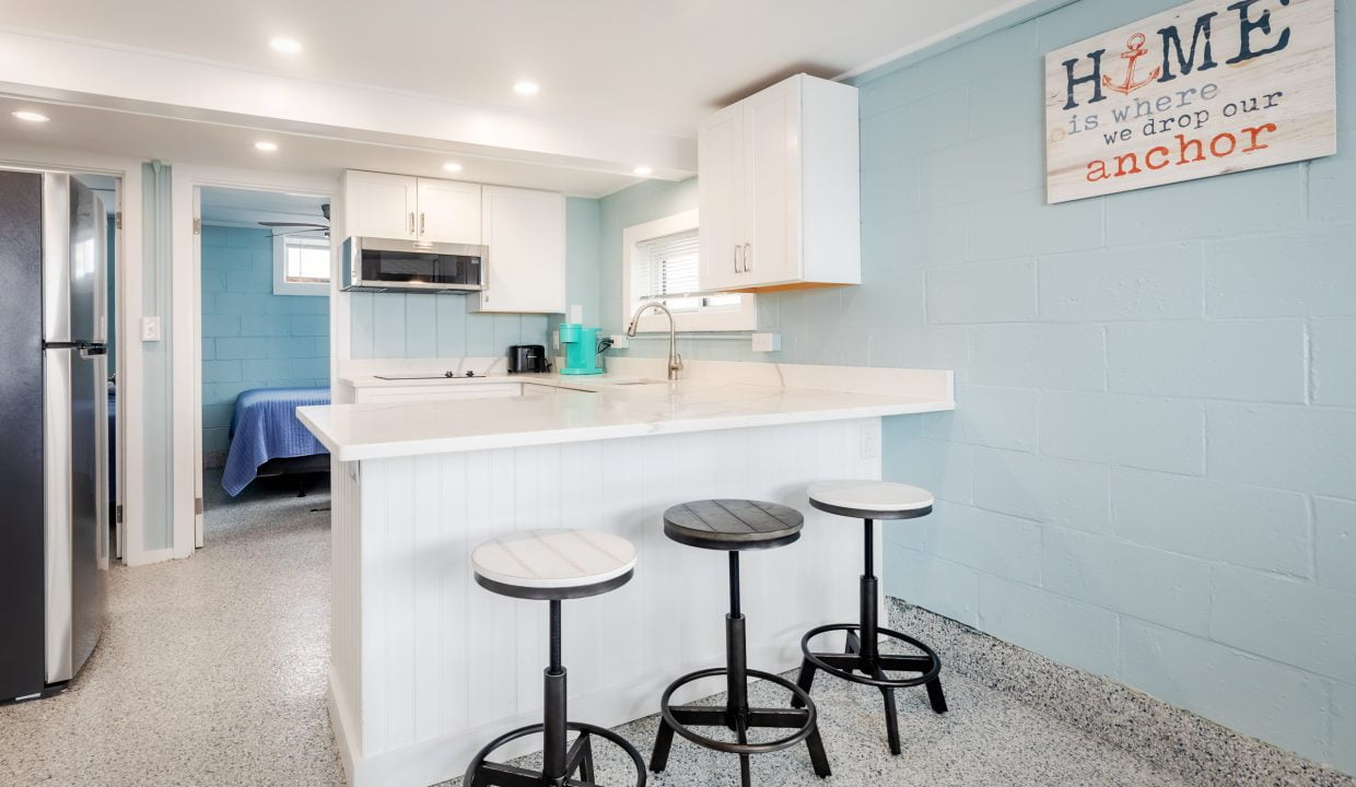 a small kitchen with blue walls and stools.