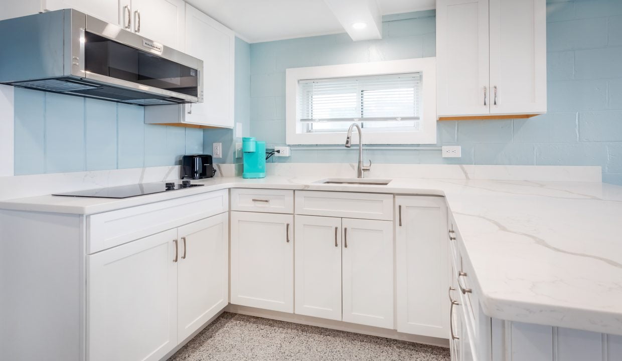 a kitchen with white cabinets and blue walls.