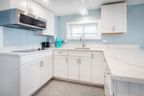 a kitchen with white cabinets and blue walls.