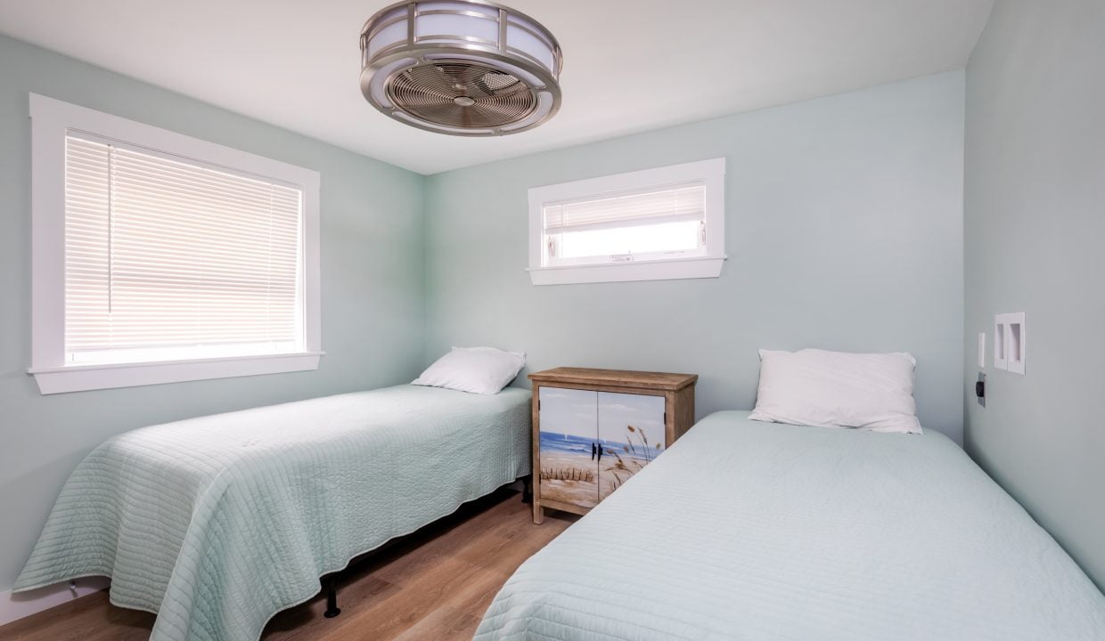 two twin beds in a room with a ceiling fan.