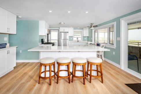 a white kitchen with blue walls and stools.