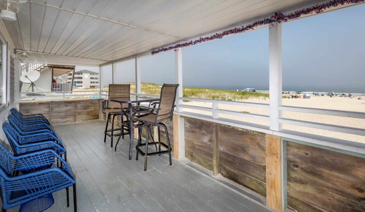 a porch with blue chairs and a view of the ocean.