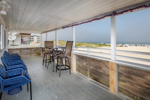 a porch with blue chairs and a view of the ocean.