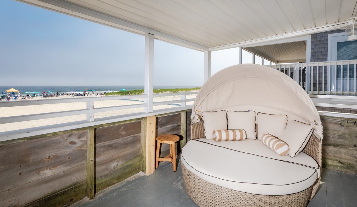 a wicker chair on a porch overlooking the ocean.