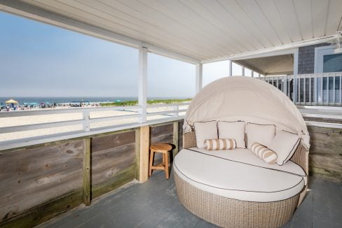 a wicker chair on a porch overlooking the ocean.