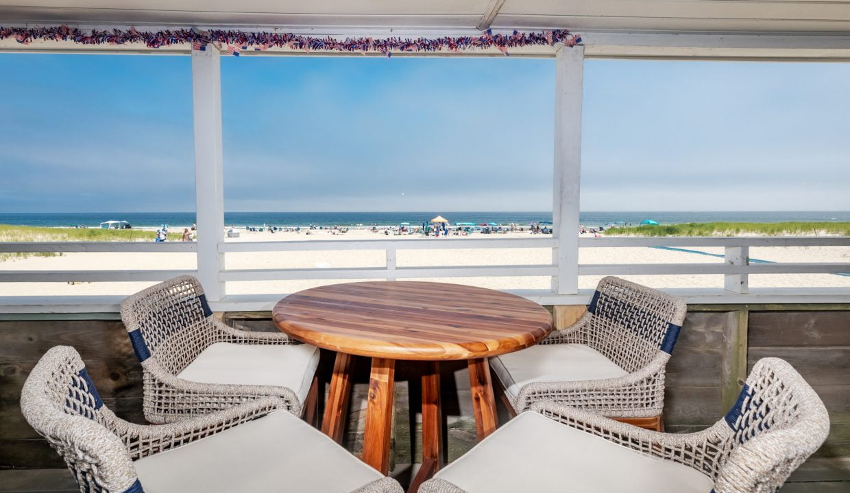 a wicker table and chairs on a balcony overlooking the beach.