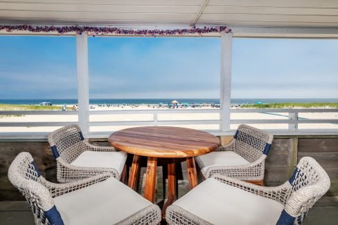 a wicker table and chairs on a balcony overlooking the beach.